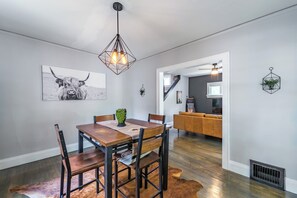 A dining area with a wooden table, chairs, and a unique geometric pendant light.
