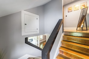 A staircase with wooden steps and a black handrail, leading to a landing with a white door and a small window.