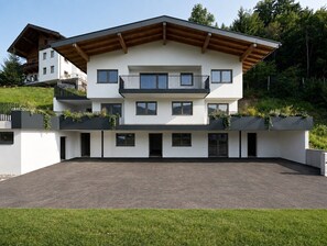 A modern two-story building with a flat roof, balconies, and a paved driveway. - The Hideaway: Arrive, unwind, and simply feel at home. (Kaltenbach)