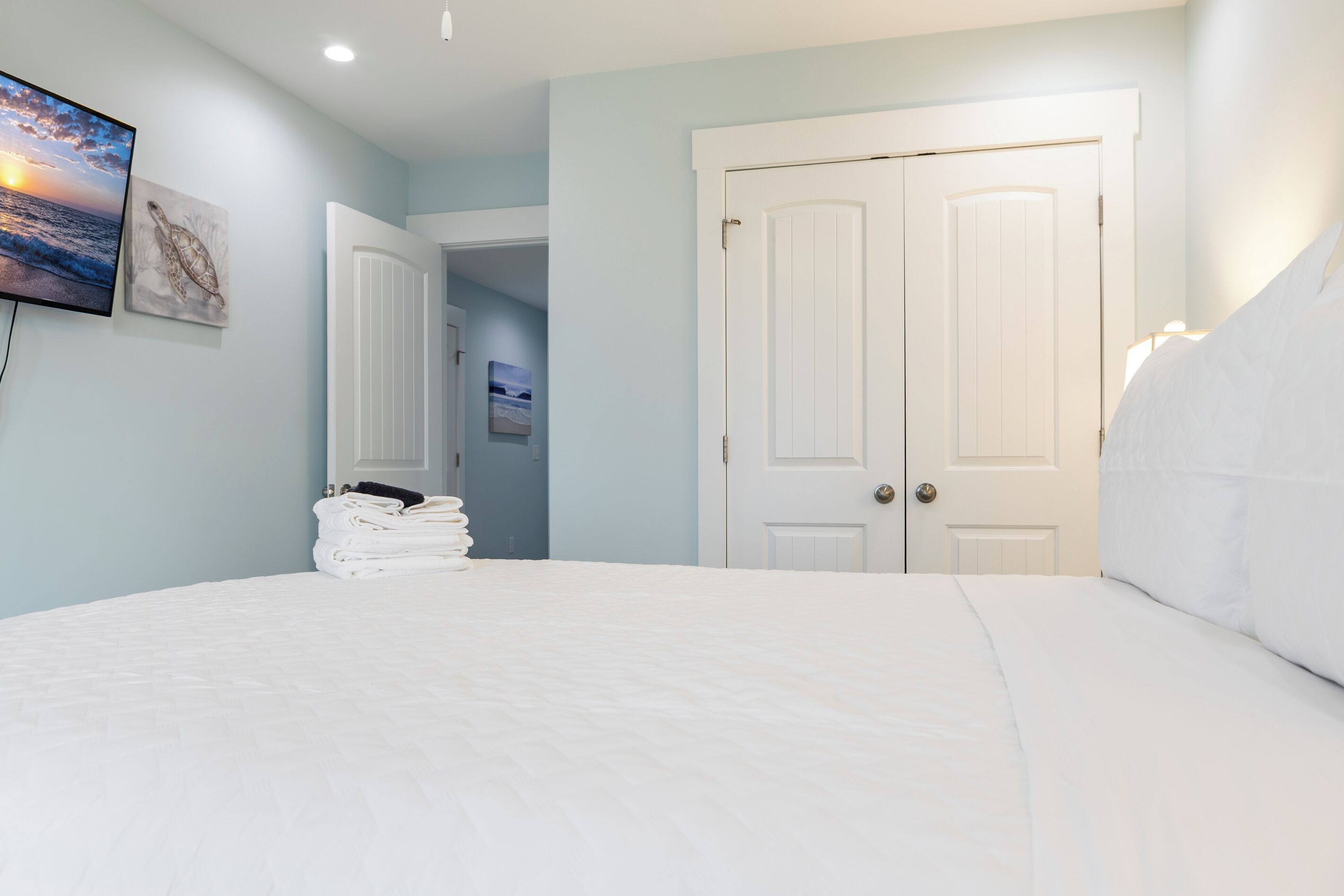 A bedroom with a bed, a television mounted on the wall, and a door.