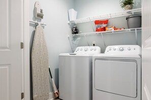 A laundry room with two front-loading washing machines, a drying rack, and a mopping bucket. - Ocean Views, Elevator, Fire Pit (Surf City)