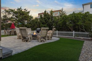 An outdoor patio with a fire pit, seating area, and a white picket fence. - Ocean Views, Elevator, Fire Pit (Surf City)