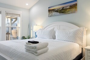 A neatly made bed with white bedding and a stack of folded towels. - Ocean Views, Elevator, Fire Pit (Surf City)