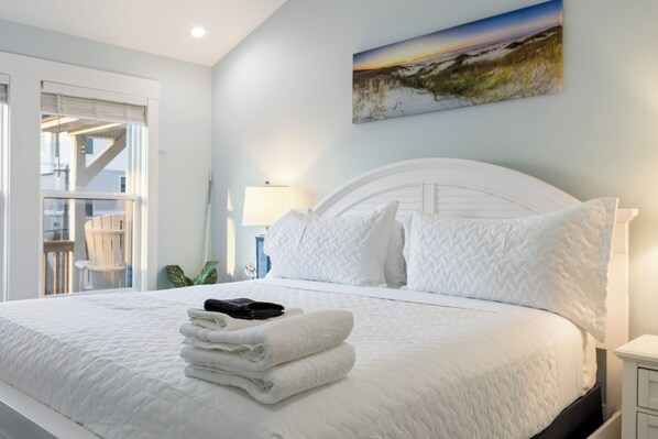 A neatly made bed with white bedding and a stack of folded towels. - Ocean Views, Elevator, Fire Pit (Surf City)
