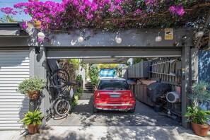 A red car parked under a covered area with a bicycle and potted plants. - Stunning Home in the Heart of Surry Hills (Surry Hills)