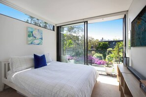 A bedroom with a large bed, a view of the outdoors, and a painting on the wall. - Stunning Home in the Heart of Surry Hills (Surry Hills)