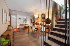 A spacious living area with a dining table, sofa, and staircase. - Stunning Home in the Heart of Surry Hills (Surry Hills)