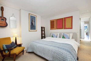 A bedroom with a bed, a chair, a guitar, and a framed picture on the wall. - Stunning Home in the Heart of Surry Hills (Surry Hills)