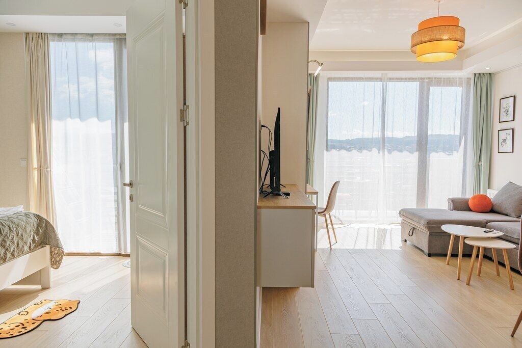 Quarto de hotel com cama, escrivaninha, sofá e vista para o mar.