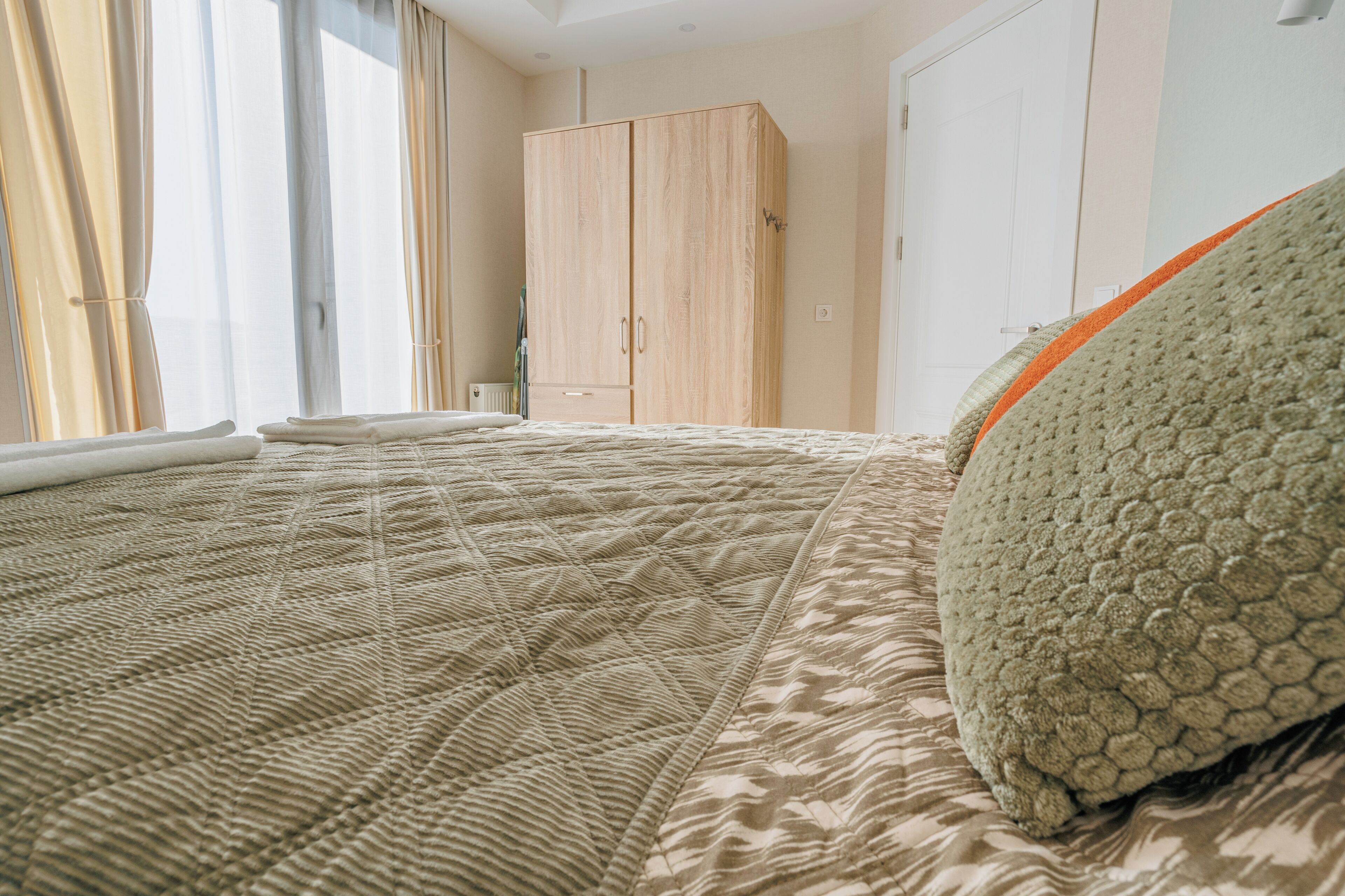 A bedroom with a bed, a wardrobe, and a window with curtains.