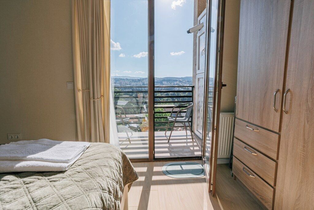 Un dormitorio con cama, armario, balcón y vistas de la ciudad, además de una puerta corrediza de cristal.