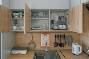 A kitchen with wooden cabinets, a built-in sink, and various kitchen utensils and dishes.