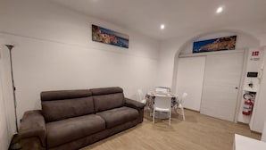A living room with a brown sofa, a dining table with chairs, and two paintings on the walls. - Cozy Apartment in La Spezia—La Spezia's Little Gem (La Spezia)