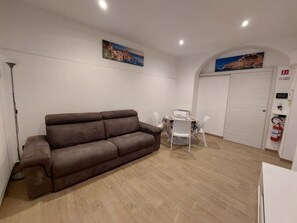 A living room with a brown sofa, a dining table with chairs, and two paintings on the walls. - Cozy Apartment in La Spezia—La Spezia's Little Gem (La Spezia)