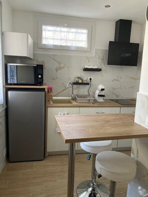 Cocina compacta con refrigerador, microondas, pileta y una pequeña mesada.