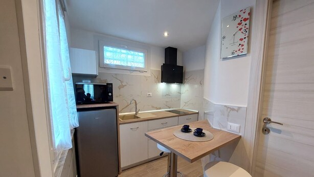 A compact kitchen with a refrigerator, microwave, sink, and a small table with two cups. - Cozy Apartment in La Spezia—La Spezia's Little Gem (La Spezia)