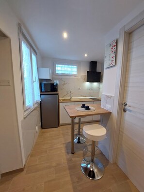 A compact kitchen with a microwave, sink, and a small dining area with a stool. - Cozy Apartment in La Spezia—La Spezia's Little Gem (La Spezia)