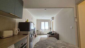 A compact living space with a kitchenette, a dining area, and a seating area with a sofa and a table. - Air-conditioned apartment in Orange's historic centre, near the Roman theatre (Orange)