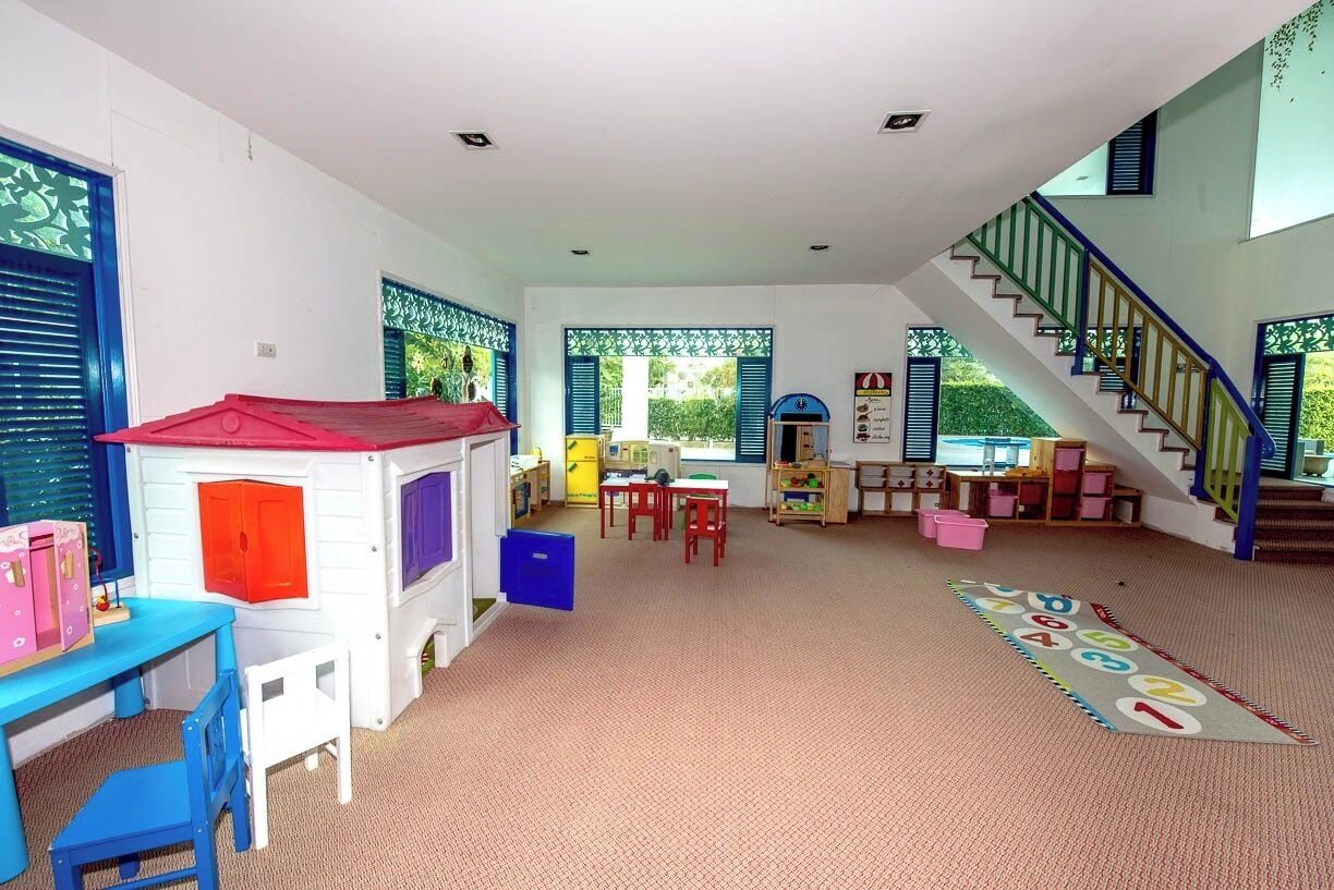 A spacious living area with a playhouse, a staircase, and a view of greenery outside.