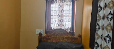 A bedroom with a single bed, a window with curtains, a ceiling fan, and a wall-mounted curtain rod.