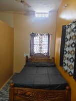 Un dormitorio con una cama individual, una ventana con cortinas, un ventilador de techo y una barra de cortina instalada en la pared.