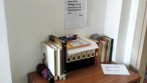 Un taulell de fusta amb una petita biblioteca, un document amb text i un quadre al mur.