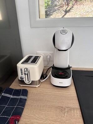 Cozinha com torradeira, cafeteira e janela.