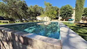 A rectangular swimming pool with a stone edge, surrounded by a grassy area and trees. - Country cottage on private property with a pool (Saint-Zacharie)