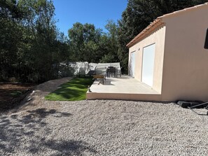 A building with a covered patio, a gravel driveway, and a green lawn area. - Country cottage on private property with a pool (Saint-Zacharie)