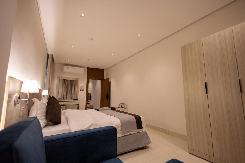 Een hotelkamer met een bed, een bureau, een kledingkast en een spiegel.