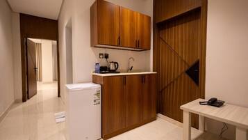 Une cuisine moderne avec des meubles en bois, un réfrigérateur, un évier et une petite table sur laquelle se trouve un téléphone.