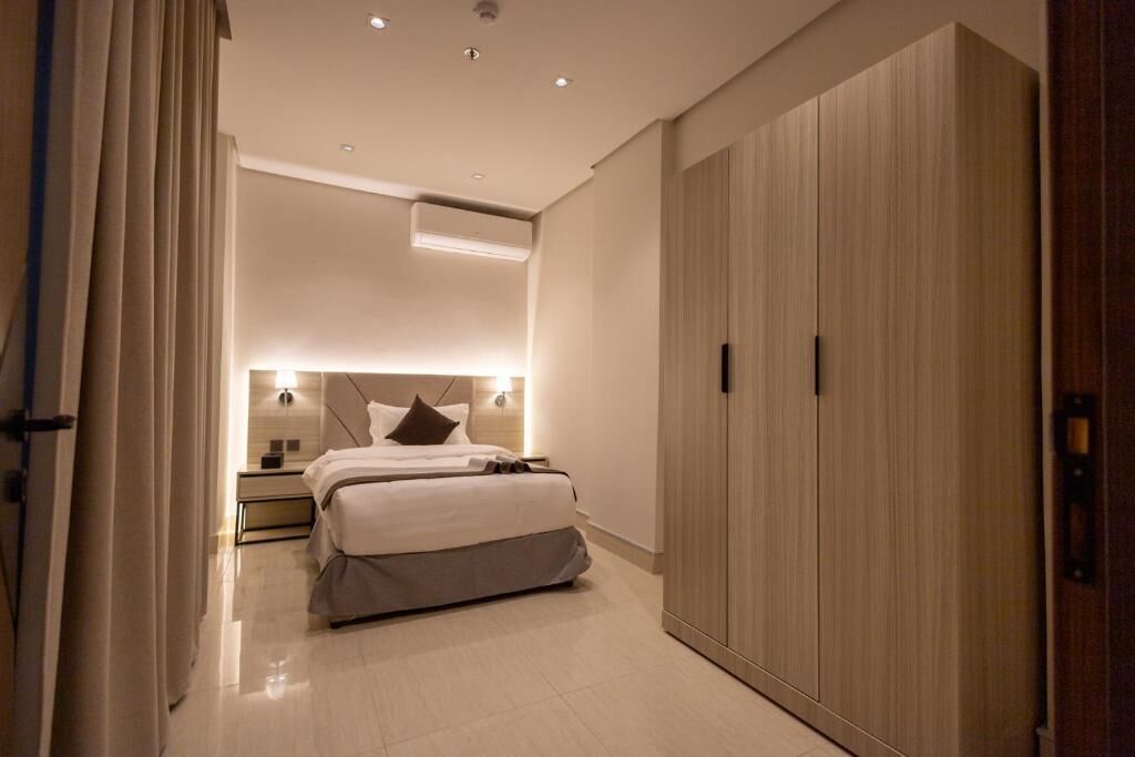 Una habitación de hotel moderna con cama, mesitas de noche, armario y aire acondicionado instalado en el techo.