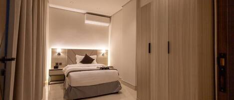 Una habitación de hotel moderna con cama, mesitas de noche, armario y aire acondicionado instalado en el techo.