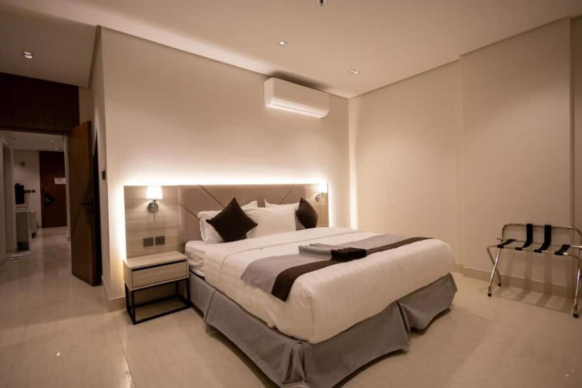 Una camera da letto moderna con un letto grande, comodini, un condizionatore d'aria a parete e una sedia.