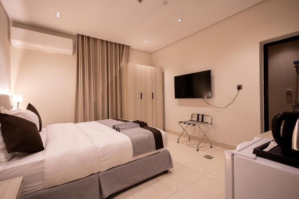 Une chambre d’hôtel équipée d’un lit, d’une télévision, d’une armoire et d’un bureau avec une chaise.