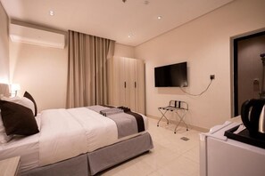 Ein Hotelzimmer mit Bett, Fernseher, Kleiderschrank und Schreibtisch mit Stuhl.