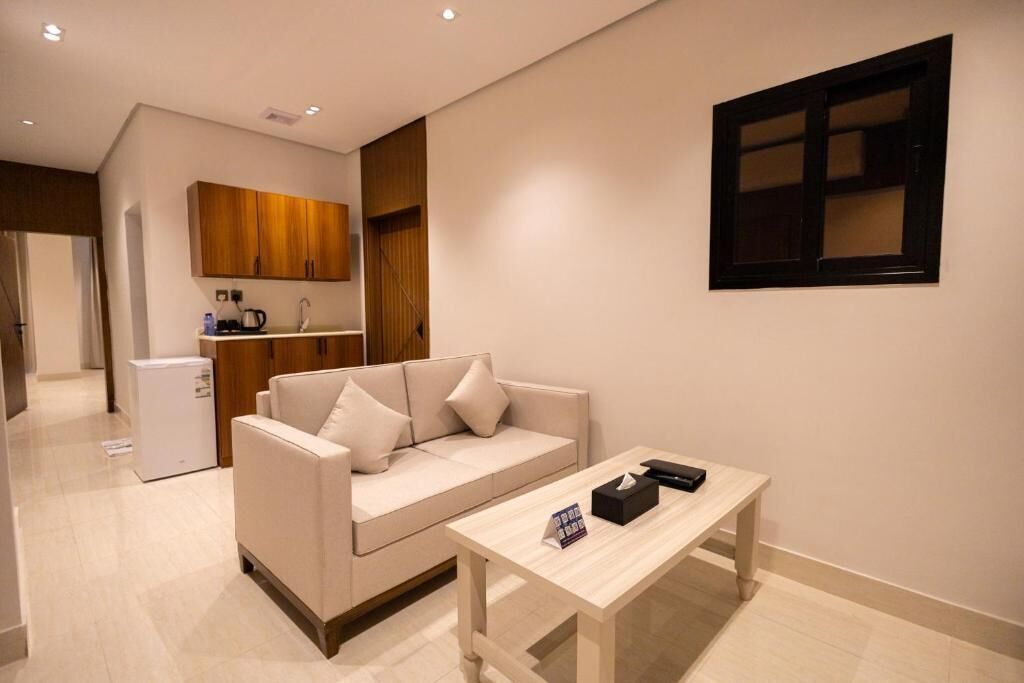 Una sala de estar moderna con un sofá, una mesa de centro y una cocina al fondo.
