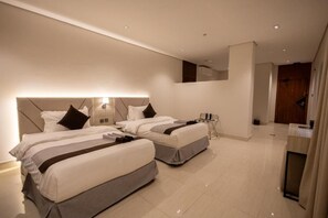 Una moderna camera d'albergo con due letti, un piccolo angolo salotto e uno specchio sopra i letti.