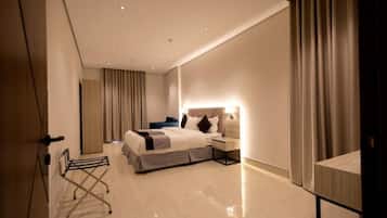 A modern hotel room with a bed, bedside table, lamp, and a small desk.