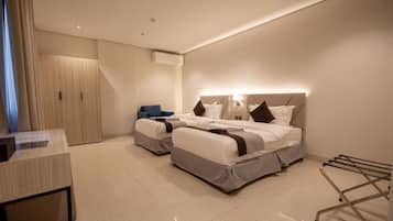 Habitación de hotel con dos camas, un escritorio, un armario y un carrito de lavandería.
