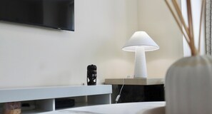 A modern bathroom with a flat-screen TV mounted on the wall, a white pedestal sink, a white lamp, and a decorative vase with reeds. - Horley 4-bedroom House, next to Gatwick Airport (Horley)