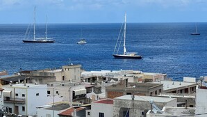 A coastal town with sailboats on the water and buildings with satellite dishes.