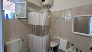 A bathroom with a toilet, a shower curtain, a sink, and a mirror.