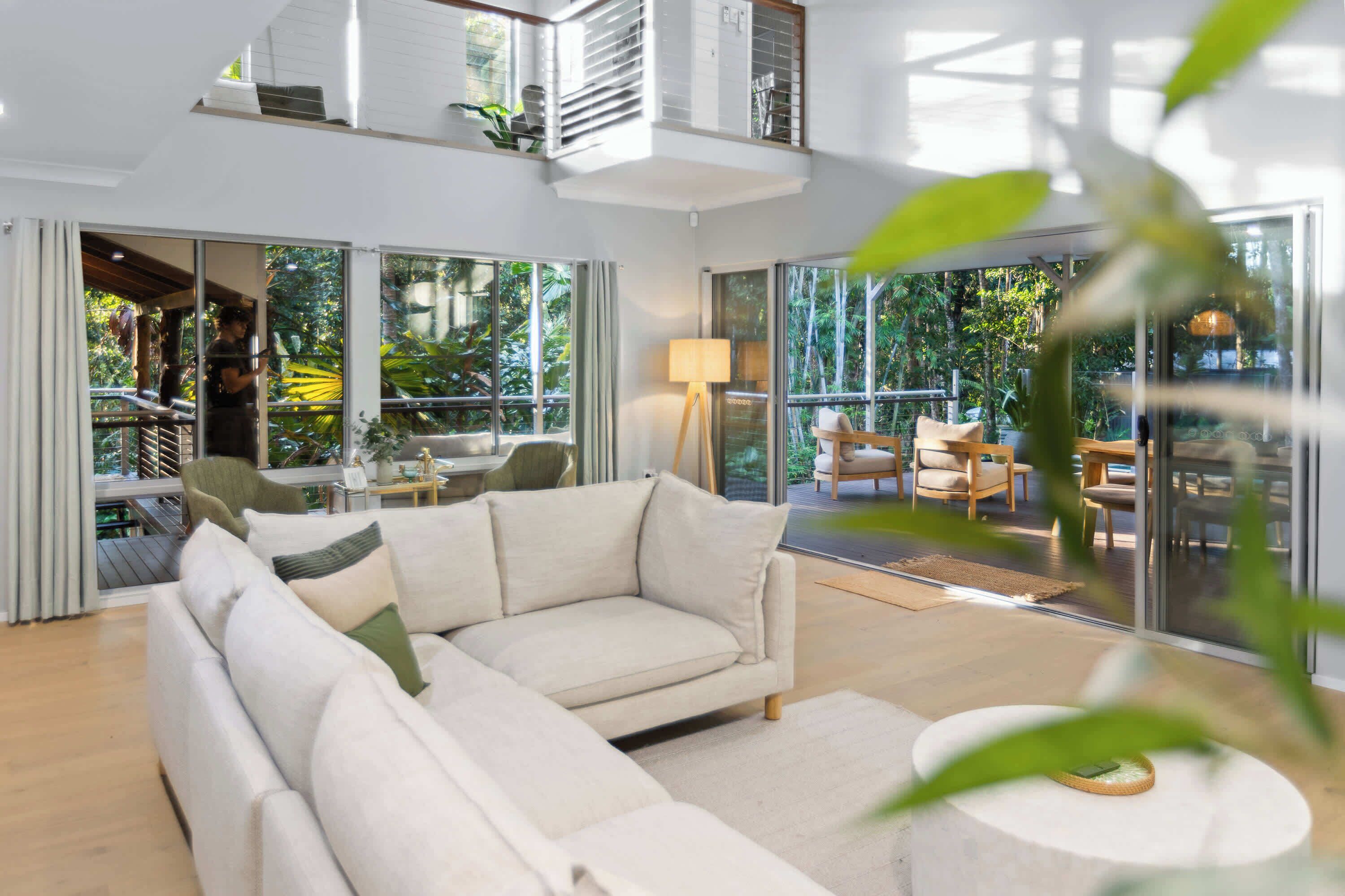 Una sala moderna con un sofá modular, una mesa de centro redonda y grandes puertas de vidrio que dan a un espacio exterior con vistas a zonas verdes.