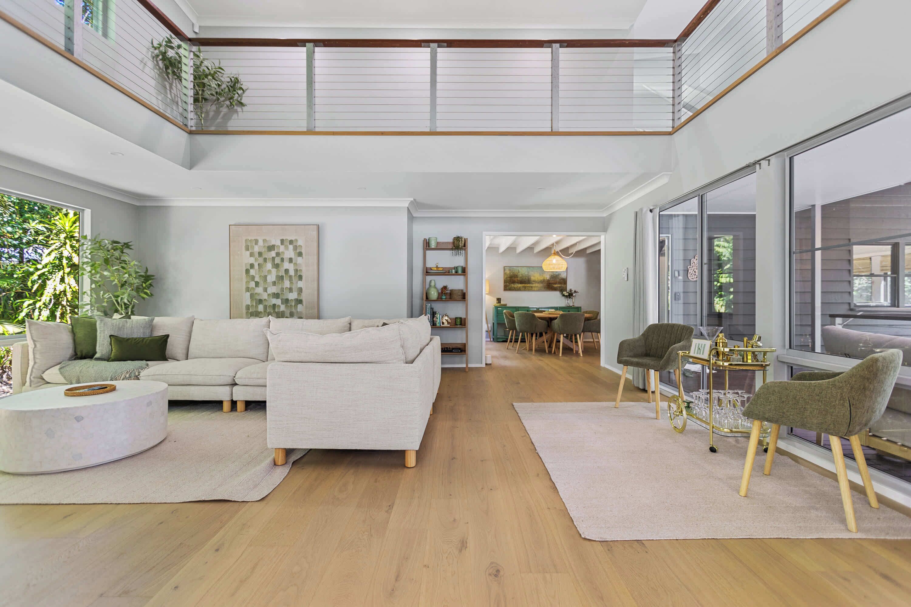 A spacious living area with a high ceiling, a dining area, and a view of the outdoors.