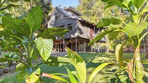 A two-story house with a covered porch and a fenced yard. - Private Kuranda Rainforest Villa with Pool (Kuranda)