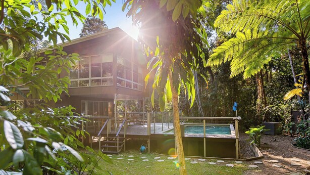 A two-story building with a pool, surrounded by lush greenery and a clear sky. - Private Kuranda Rainforest Villa with Pool (Kuranda)