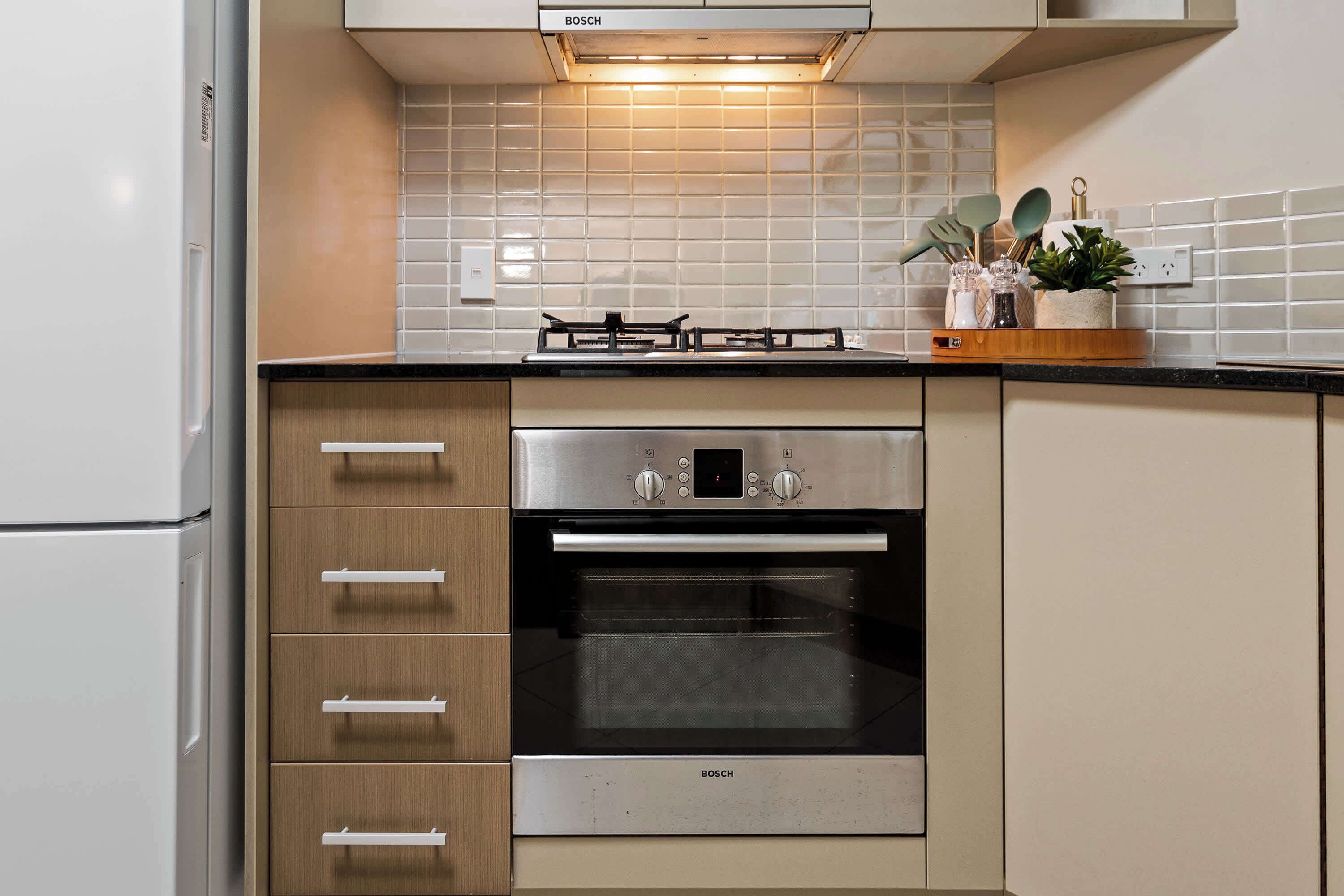 A kitchen with a Bosch oven, a gas stove, and a refrigerator.