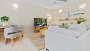 Uma sala de estar moderna com televisão de tela plana, ventilador de teto e uma área de jantar com mesa e cadeiras.