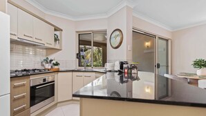 Cozinha moderna com forno Bosch, máquina de café e uma janela grande com vista para o exterior.